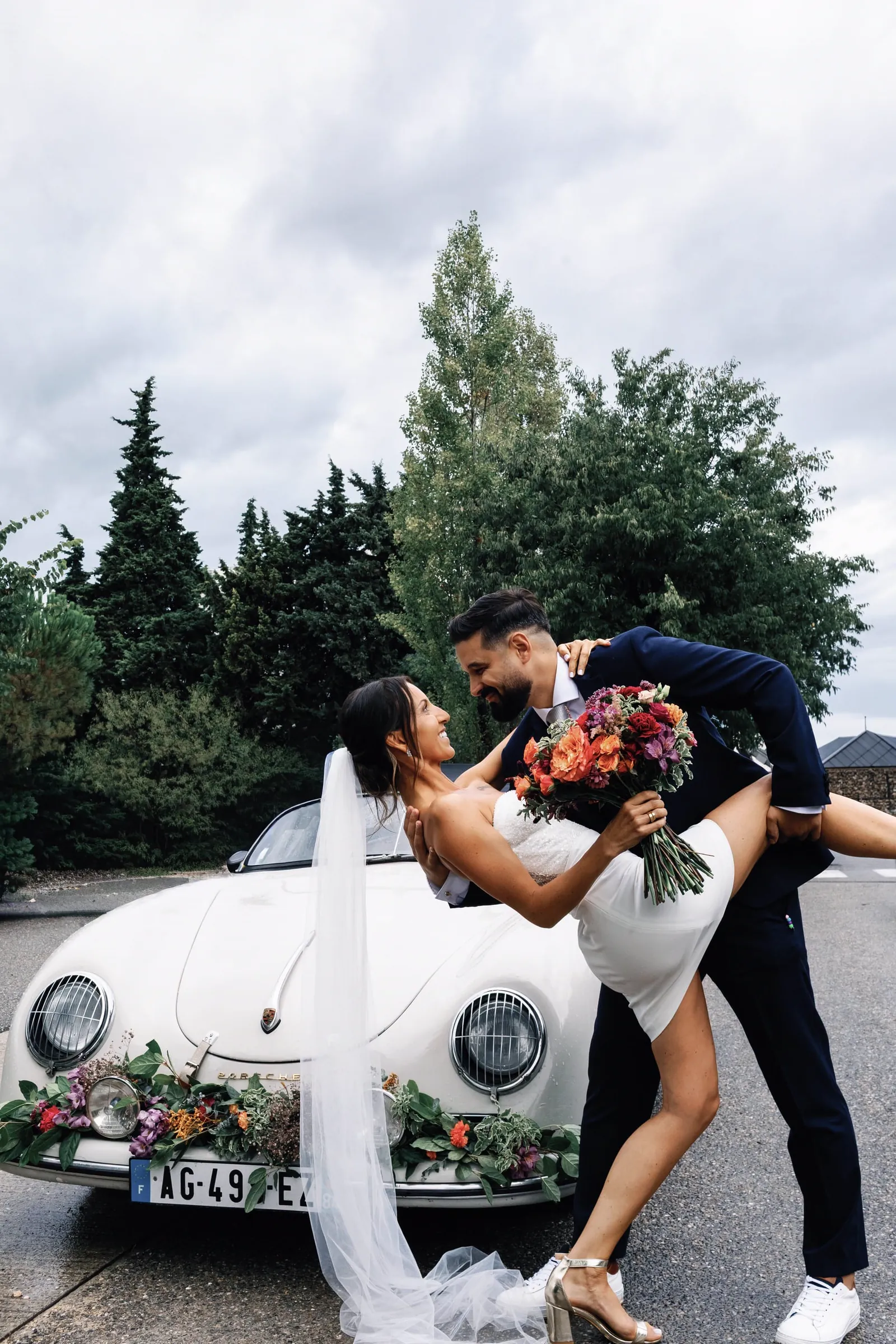Newlyweds beside a vintage car decorated with flowers