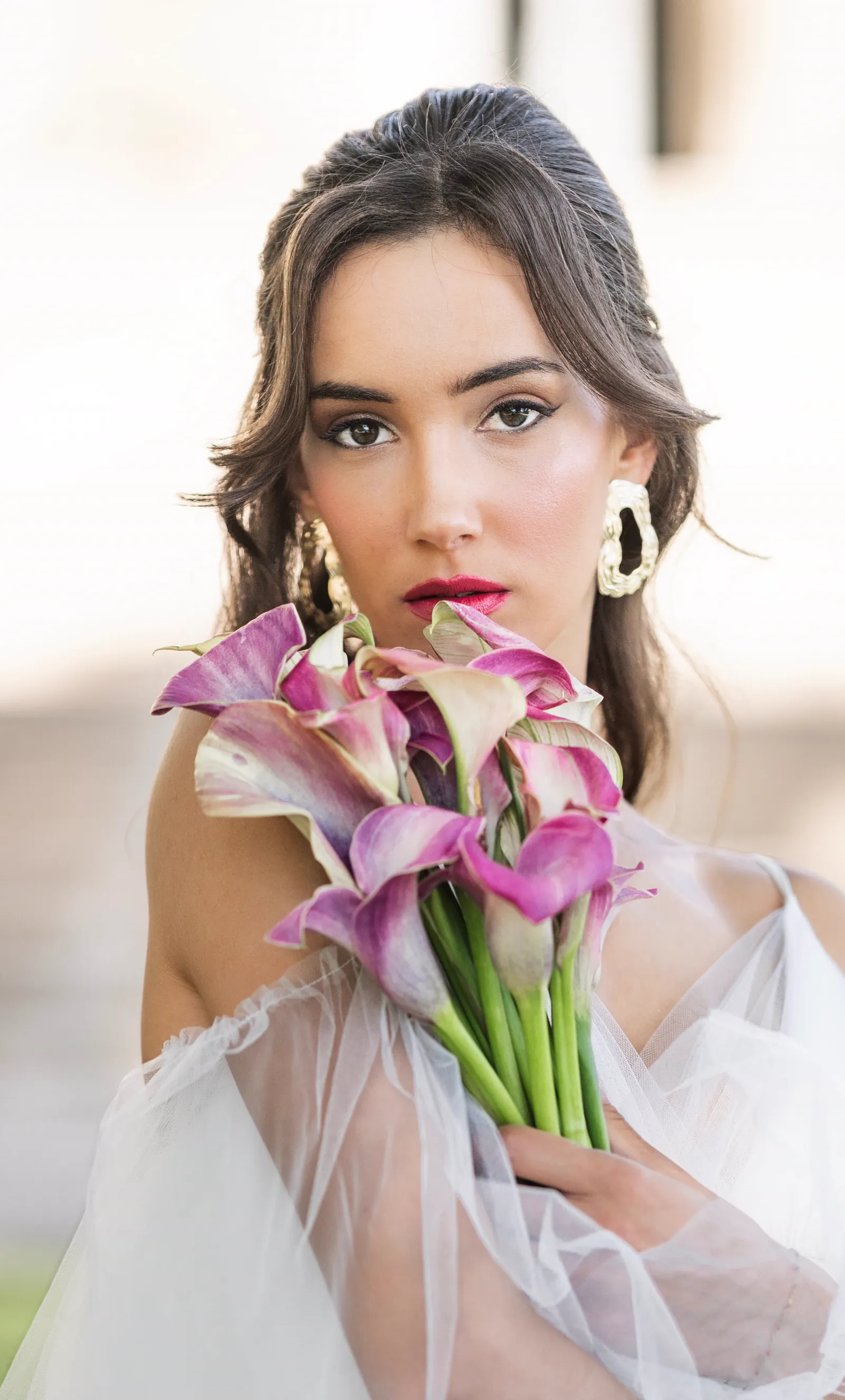 Mariée tenant un bouquet d'arums devant un château
